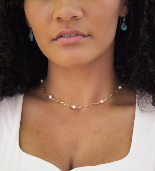 White freshwater pearls set onto a gold paperclip style chain. Modeled image.