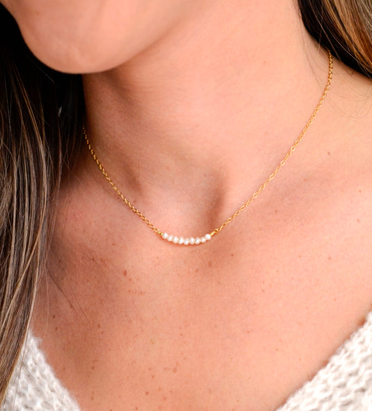 Modeled image of white freshwater pearl bar necklace shown in 14k gold filled. The peals are small and slightly irregular in shape.