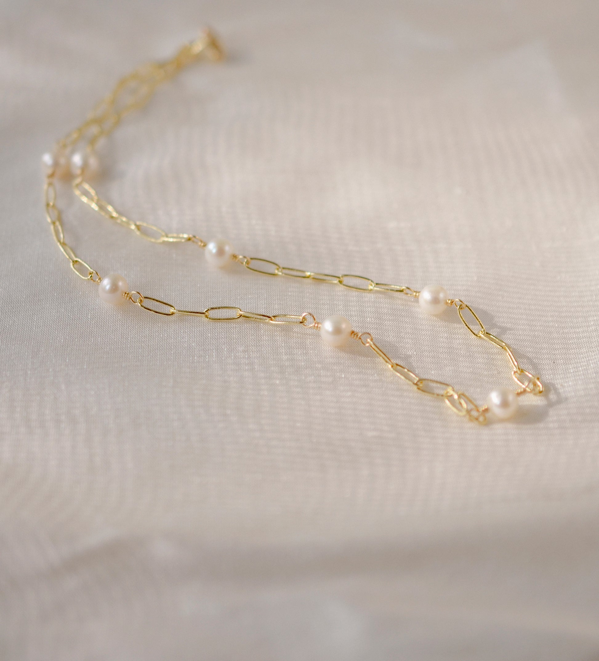 White freshwater pearls set onto a gold paperclip style chain. 