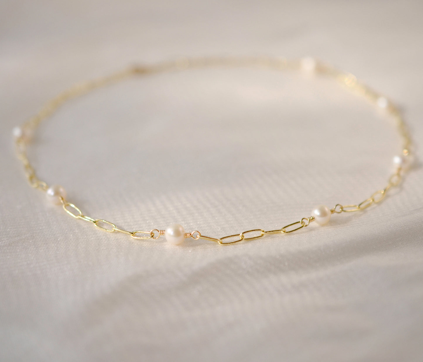 White freshwater pearls set onto a gold paperclip style chain.
