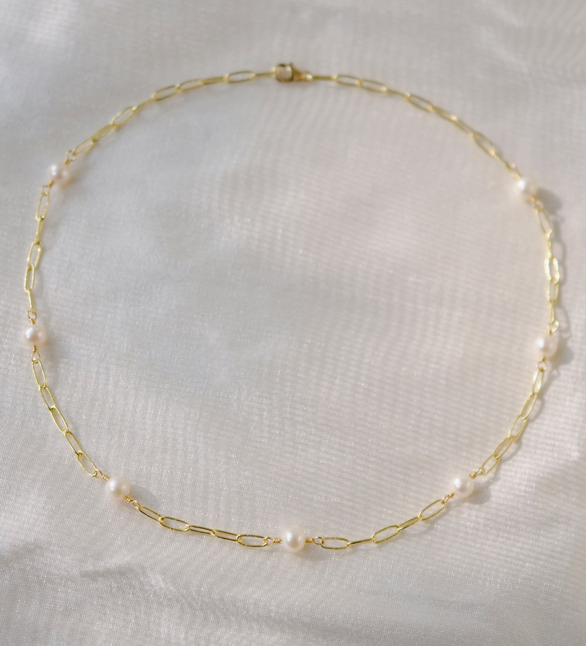 White freshwater pearls set onto a gold paperclip style chain. The paperclip style has elongated links.