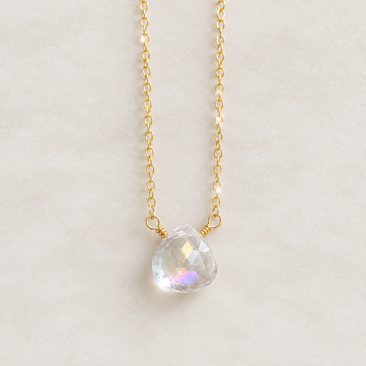 A heart shaped briolette teardrop faceted mystic topaz crystal set on a 14k gold filled chain. The dainty gemstone is clear and shifts rainbow colors with movement. This necklace is handmade in Connecticut by Gemnia and also available in sterling silver. 