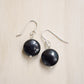 Natural smooth polished coin shape black Shungite dangle from sterling silver earring hooks. 