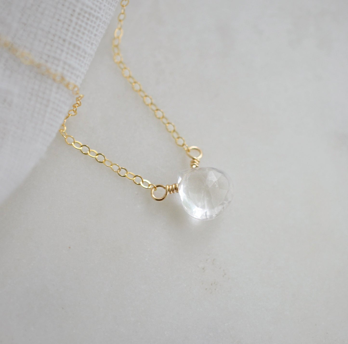 A clear, natural crystal quartz faceted teardrop set onto a 14k gold filled chain.