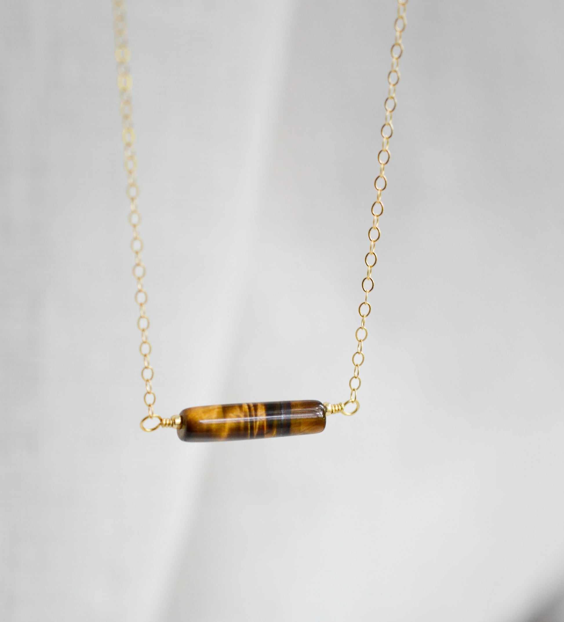 Tiger Eye gemstone necklace. A smooth polished Tiger Eye stone in a bar or tube shape set onto a 14k gold filled chain.