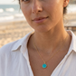 Woman wearing a gold necklace with a turquoise stone pendant. This jewelry is handmade in Connecticut by Gemnia.