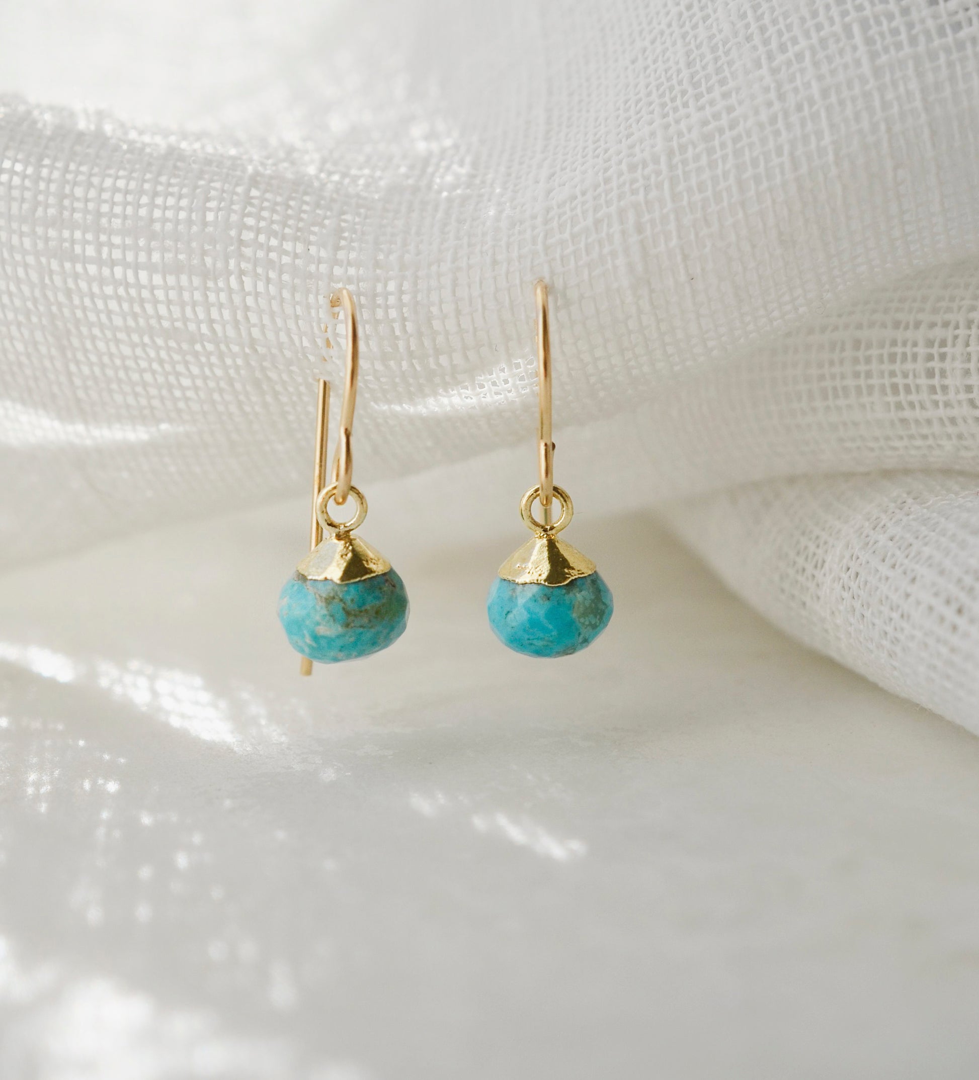 Small round turquoise faceted drops suspended from gold filled earwires. Each stone has a different matrix with light to dark brown coloring.