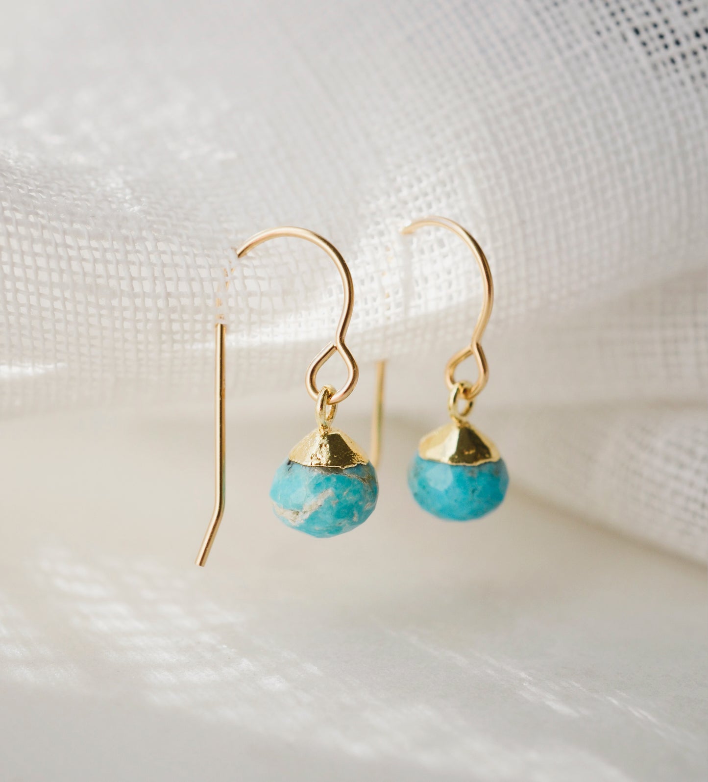 Small round turquoise faceted drops suspended from gold filled earwires. Each stone has a different matrix with light to dark brown coloring.