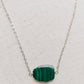 Natural green Malachite smooth polished slice with raw edges. Each stone is an irregular oval shape and has a variety of banding. Shown on a sterling silver chain.