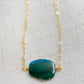 Natural green Malachite smooth polished slice with raw edges. Each stone is an irregular oval shape and has a variety of banding. Shown on a 14k gold filled chain.