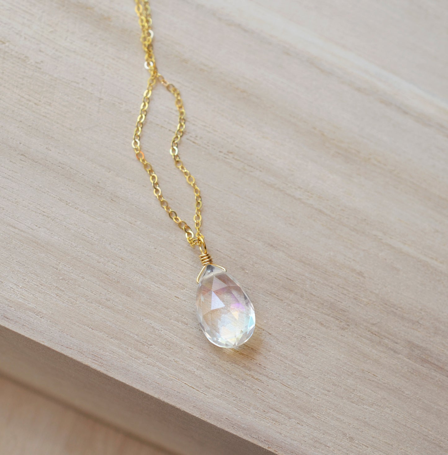 Rainbow hues shown within the Mystic Topaz. The gemstone is a faceted teardrop shape. The 14k gold filled style is shown.