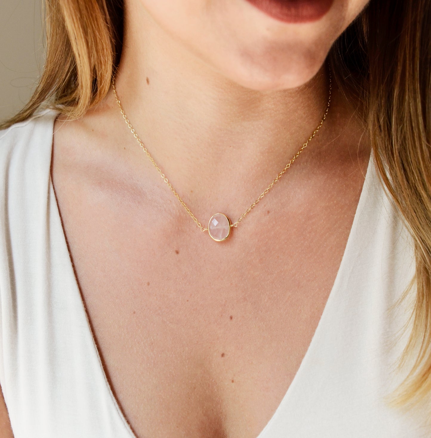 Dainty pink Rose Quartz oval coin shaped pendant with gold bezel. Chain is 14k Gold Filled. Modeled Image
