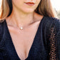 A woman is wearing a natural white howlite necklace. The stone is round with natural gray marbling and set on a 14k gold filled chain. Also available in sterling silver. 