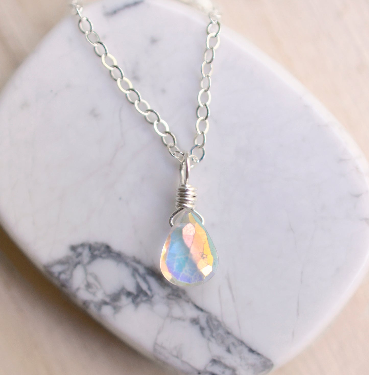 Rainbow Quartz teardrop crystal on a sterling silver chain. The stone flashes a shimmering array of rainbow colors. 