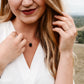 A modeled image of a woman wearing a rough, genuine, black tourmaline crystal necklace in sterling silver. The minimalist jewelry is handmade in Connecticut. 