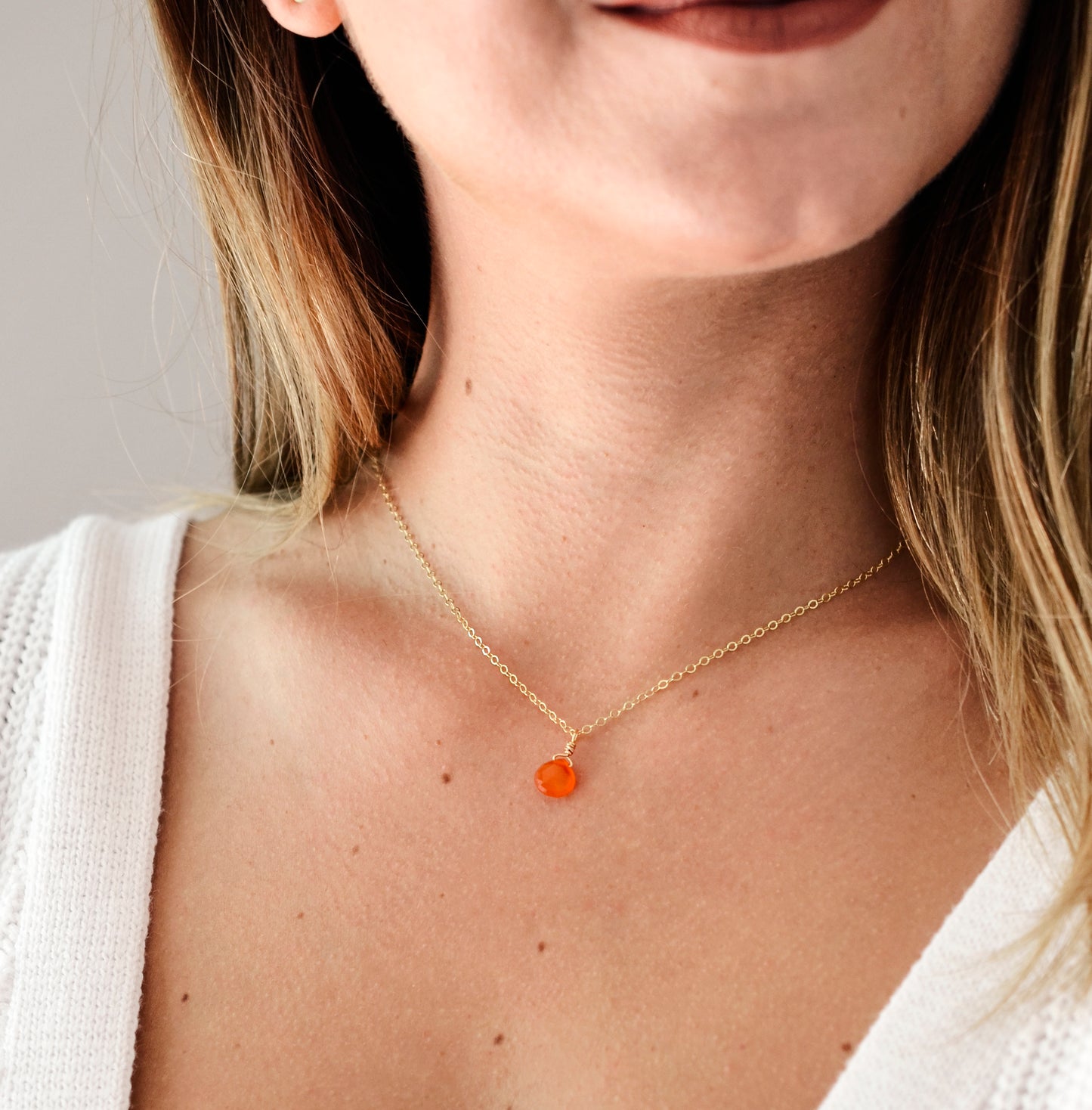 Natural orange Carnelian teardrop gemstone set onto a 14k gold filled chain. Modeled image.