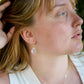 A woman wearing a clear rainbow mystic topaz faceted teardrop earring in 14k gold filled. The crystal is clear, but shifts rainbow colors with movement. Handmade gemstone jewelry by Gemnia. 