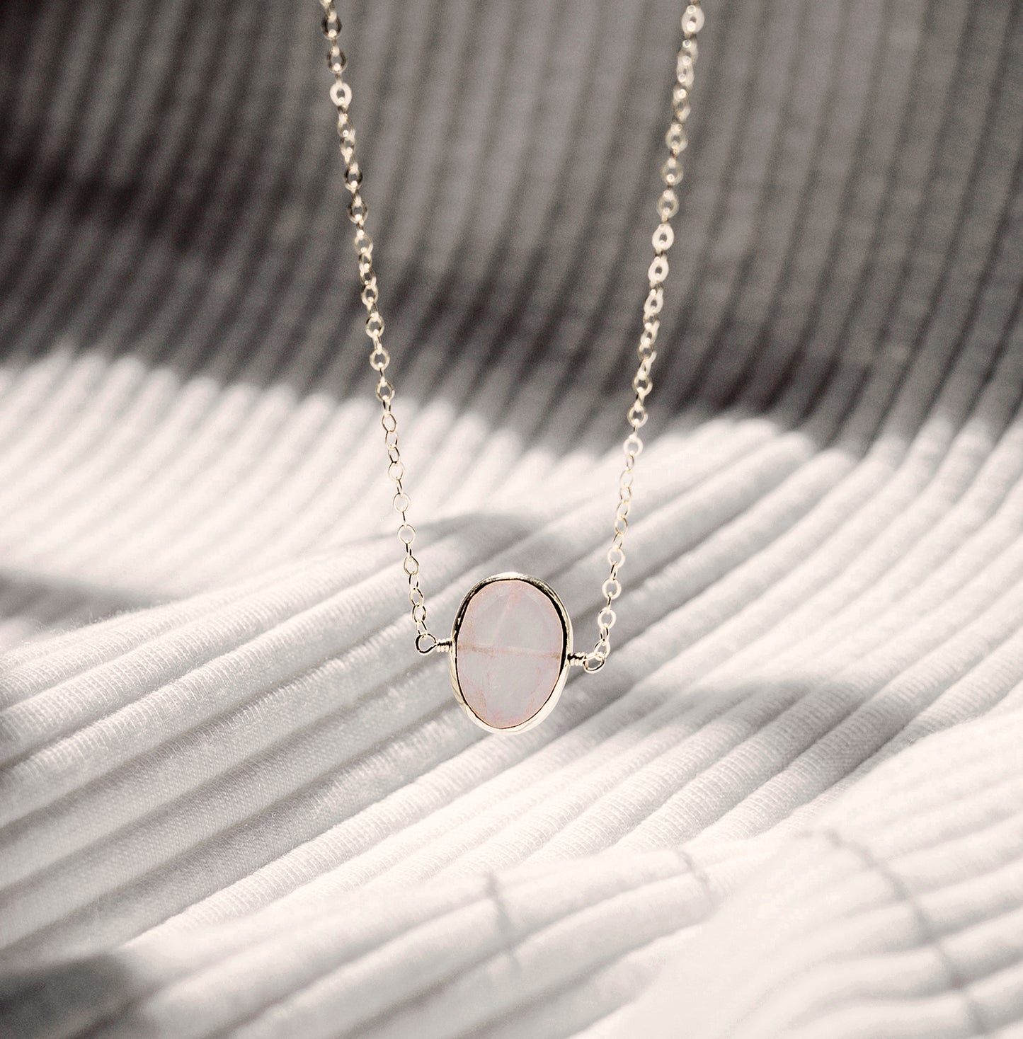 Dainty pink Rose Quartz oval coin shaped pendant with silver bezel. Chain is sterling silver.