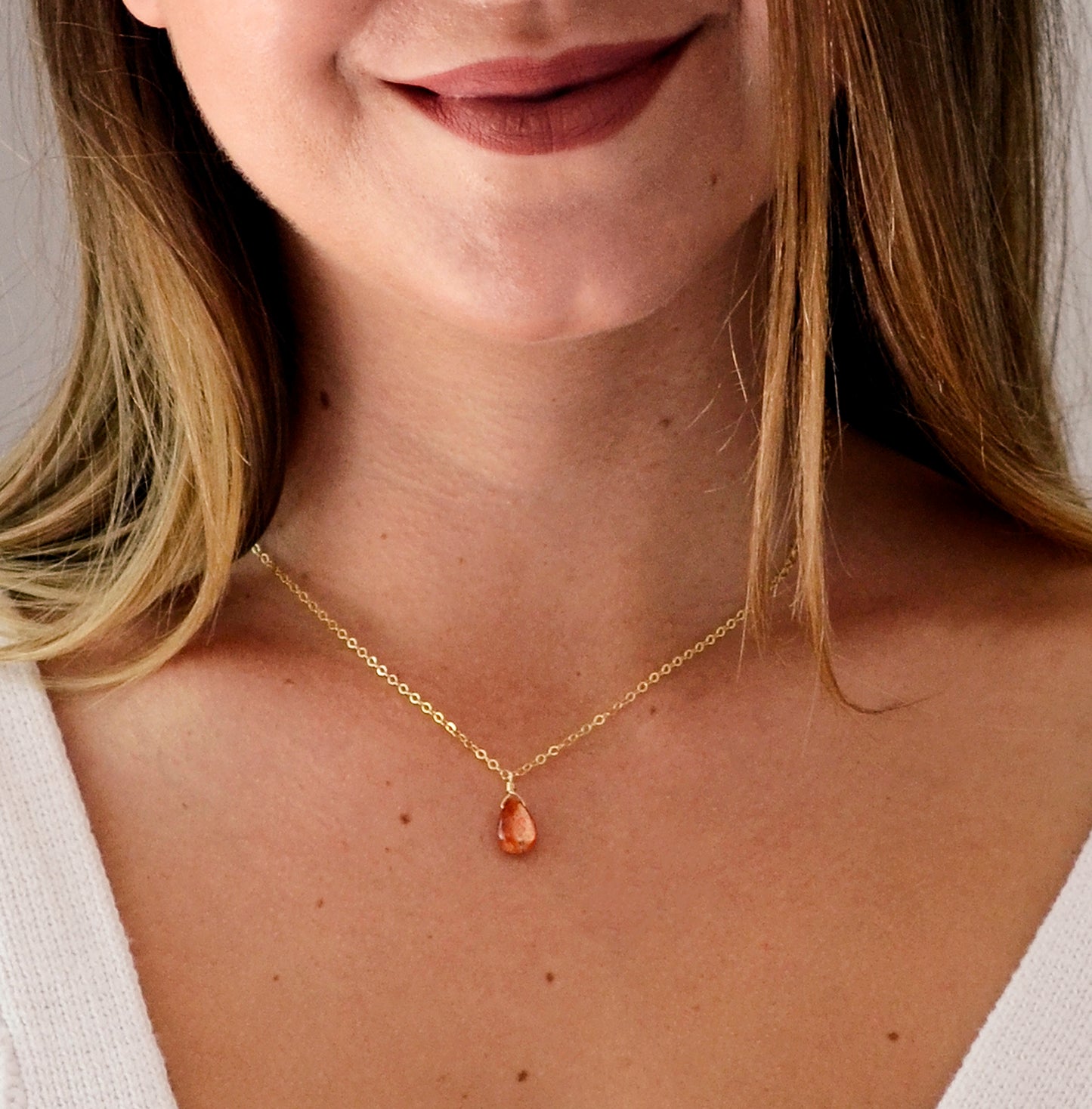 Orange Sunstone smooth polished teardrop pendant on a 14k gold filled chain. Modeled on a 16 inch chain.